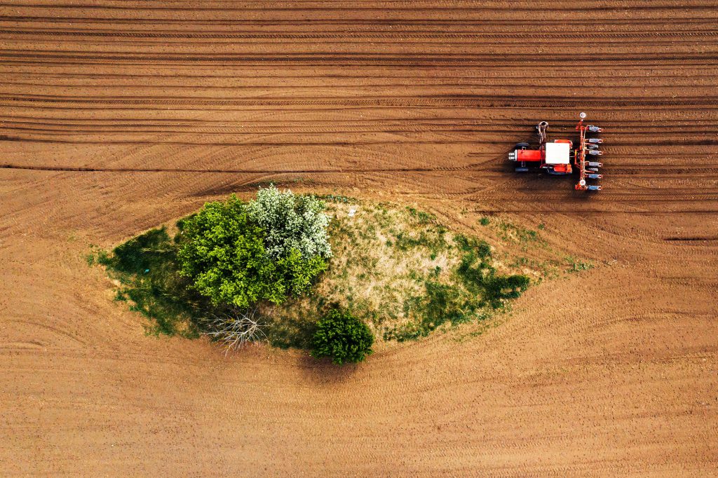 Farmer and tractor with seeder from drone pov